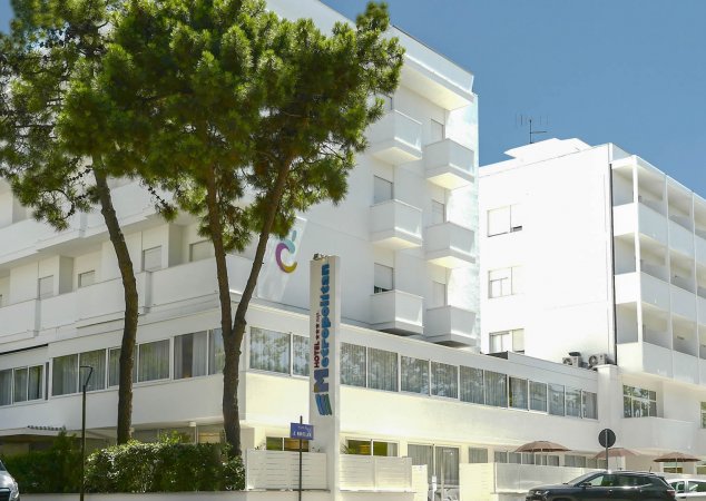 Edificio bianco con alberi sul davanti.