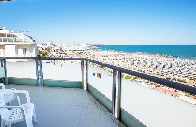 Balcone con vista mare e sedie bianche.