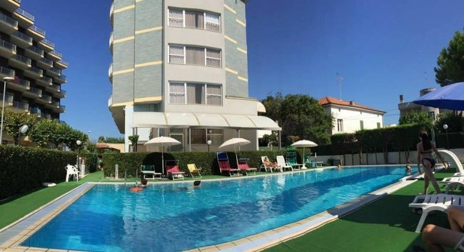 Piscina all'aperto con lettini e ombrelloni.