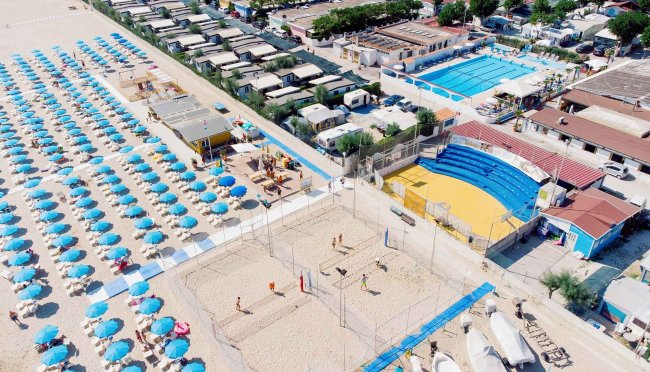 Spiaggia con ombrelloni blu e campi da beach volley.