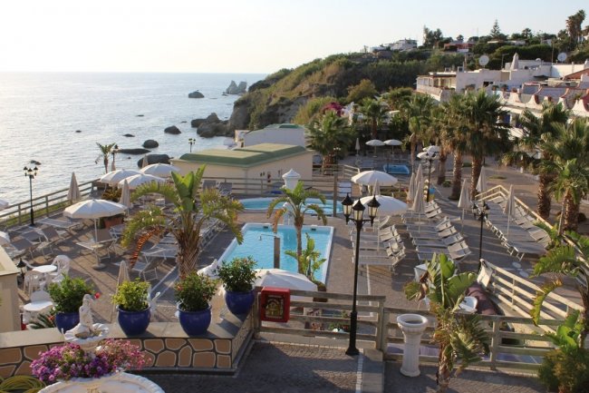 Piscina con lettini e vista mare.