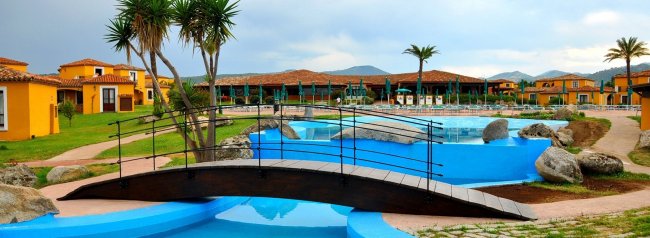 Ponte di legno su piscine azzurre circondate da edifici gialli.