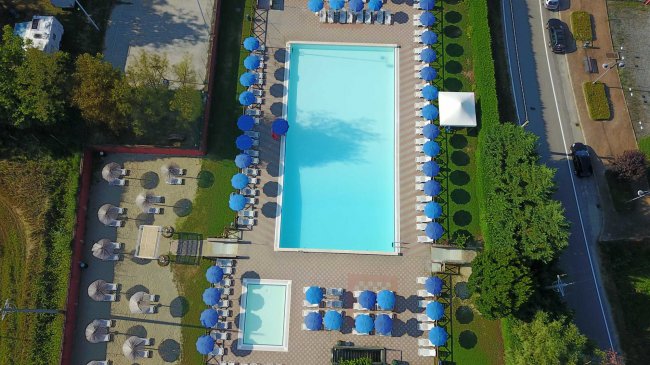 Vista dall'alto di una piscina con ombrelloni blu.
