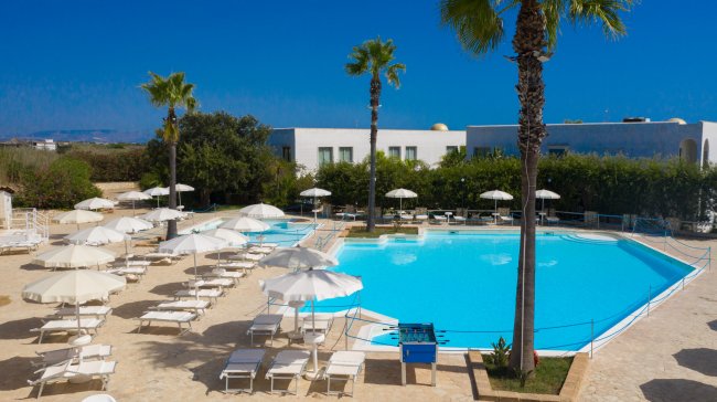 Piscina circondata da sedie a sdraio e ombrelloni.