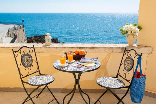 Tavolo con sedie vista mare, succhi e frutta.