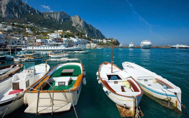 Piccole barche ormeggiate in un porto con montagne.