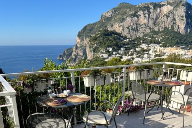 Terrazza con tavoli, vista mare e montagne.
