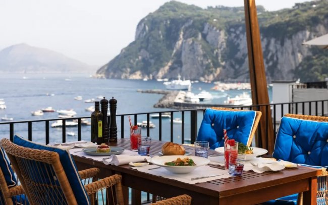Tavolo da pranzo all'aperto con vista sul mare e le rocce.