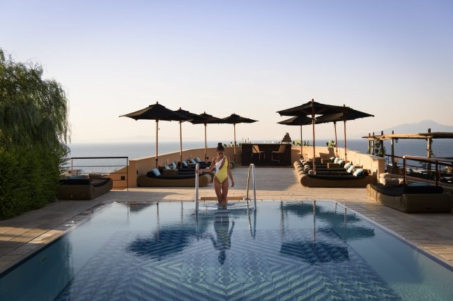 Piscina con vista mare e lettini.