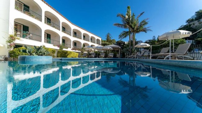 Piscina con palme e edificio bianco.