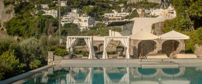 Piscina con tende bianche e sfondo collinare.