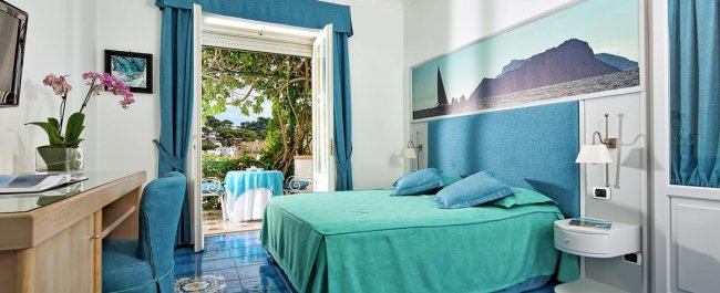 Camera turchese con vista su giardino e montagna.