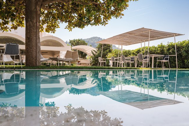 Piscina riflettente sedie e struttura in giardino.