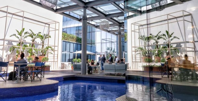 Patio moderno con tavoli e piante interne.