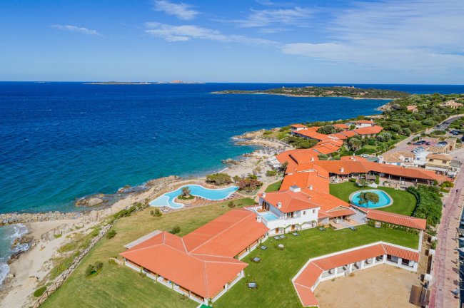 Vista aerea di complesso con tetti rossi e mare.