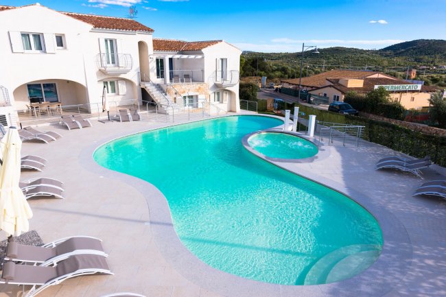 Piscina di forma irregolare in un cortile soleggiato.