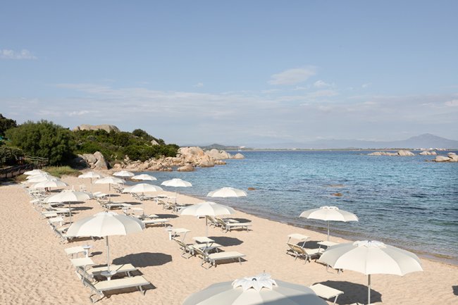 Spiaggia con lettini e ombrelloni bianchi.