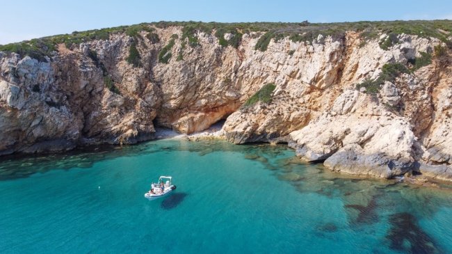 Barca ormeggiata in baia di rocce.