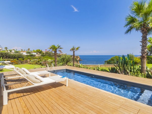 Piscina su terrazza con vista mare e palme.
