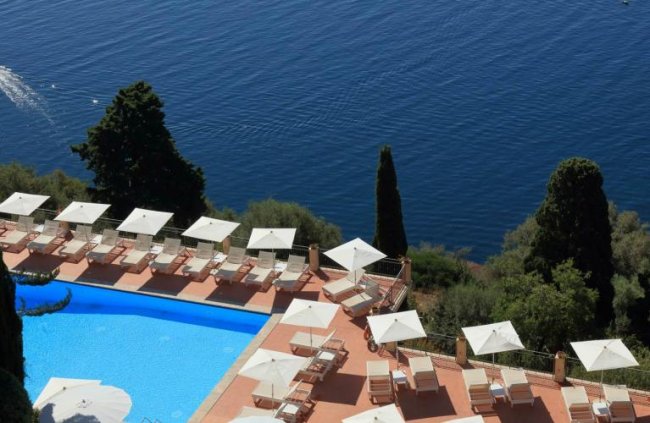 Piscina con lettini e ombrelloni vicino al mare.
