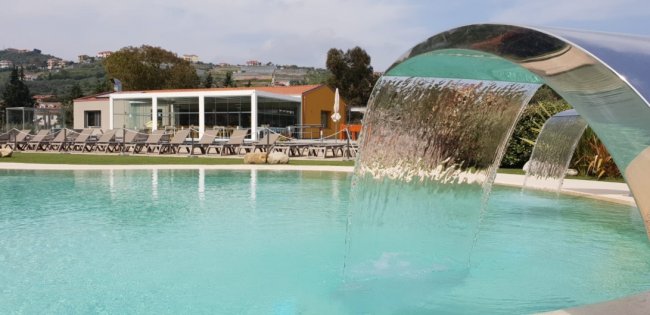 Piscina con cascata e lettini in lontananza.