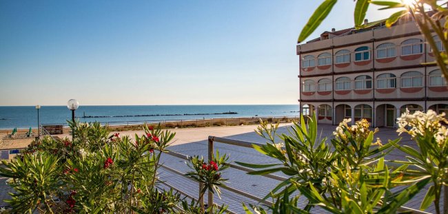 Edificio con vista mare e piante in primo piano.