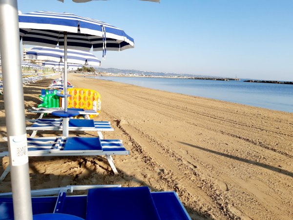 Ombrelloni blu e bianchi su una spiaggia sabbiosa vicino al mare.