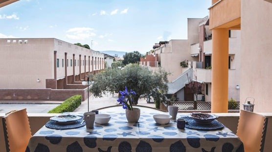 Tavolo apparecchiato su un balcone con vista cortile.