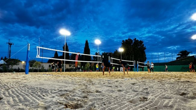 Campo da beach volley con giocatori di sera.