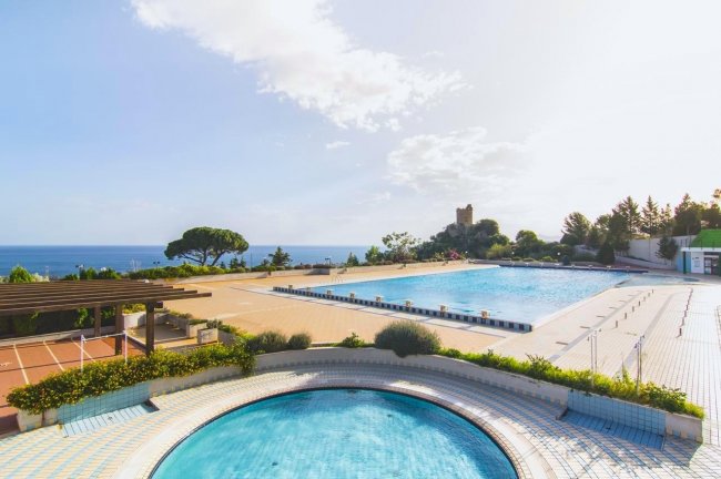 Piscina all'aperto con vista sul mare e cielo sereno.