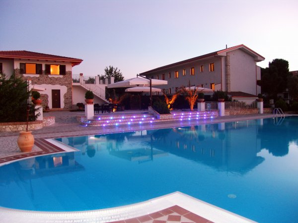 Piscina illuminata al crepuscolo vicino a edifici.