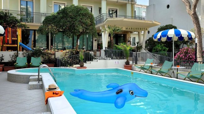 Piscina con gonfiabile blu davanti a un hotel.
