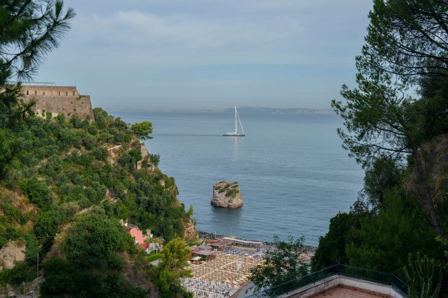 Vista panoramica su mare con barca e scogliera.