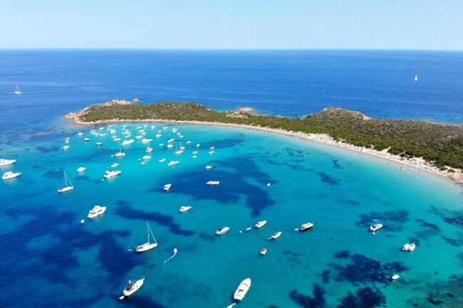 Costa con barche su mare azzurro.