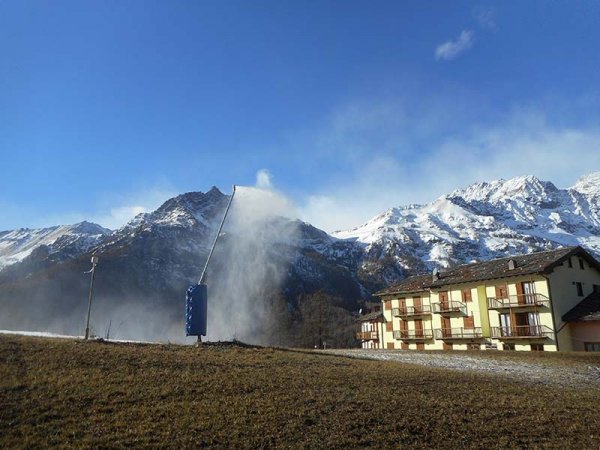 Paesaggio montano innevato con edificio e cannone da neve.