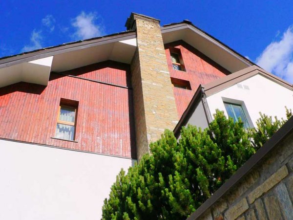Casa con facciata in legno e mattoni, cielo blu.