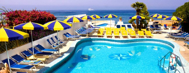 Piscina blu con ombrelloni gialli e blu, vista mare.