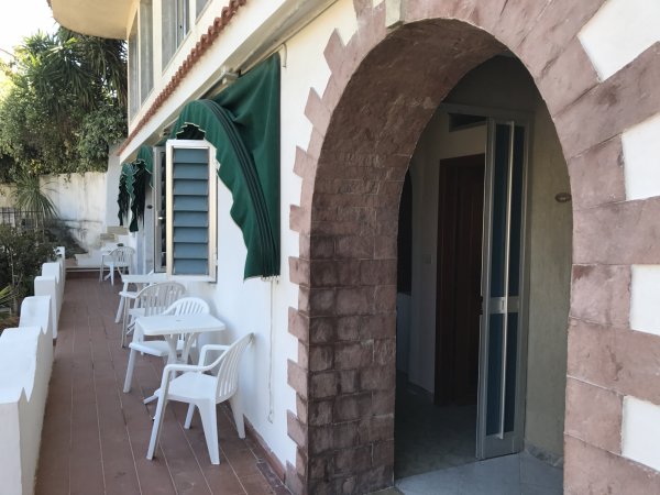 Veranda con arco e sedie bianche.