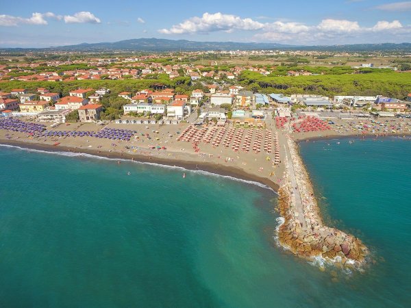 Spiaggia affollata con ombrelloni colorati e un lungo molo.