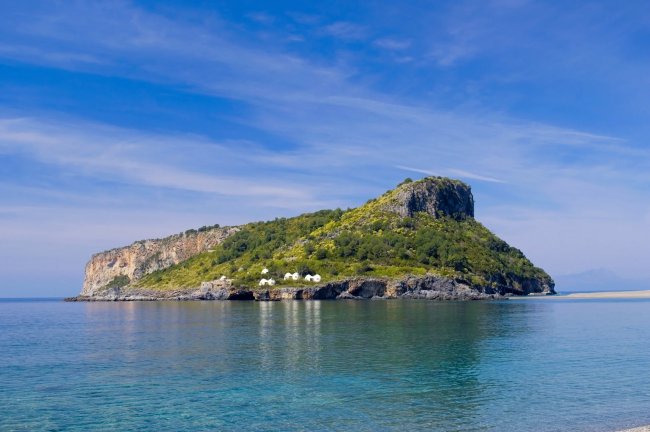 Isola verde con scogliera e mare calmo.