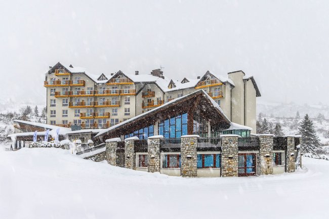Hotel innevato con balconi e grandi finestre.
