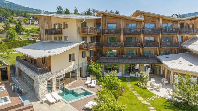 Hotel estivo con piscina, giardino, e terrazze in legno.