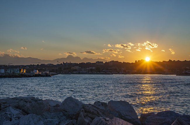 Tramonto sopra un mare calmo con rocce.
