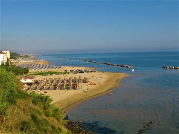 Spiaggia con lettini, mare e scogli.