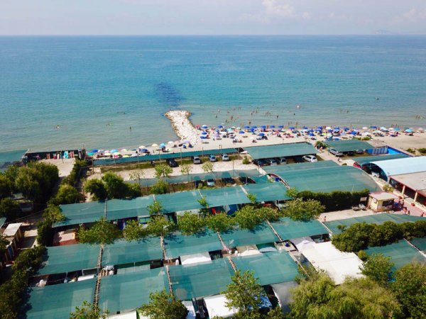 Vista aerea di un campeggio e spiaggia con ombrelloni.