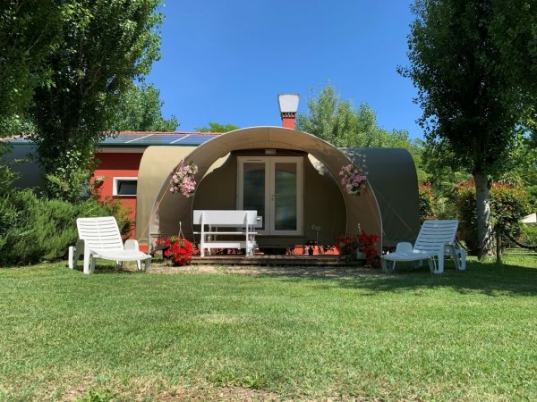 Piccolo bungalow con panchina e sedie a sdraio nel giardino.