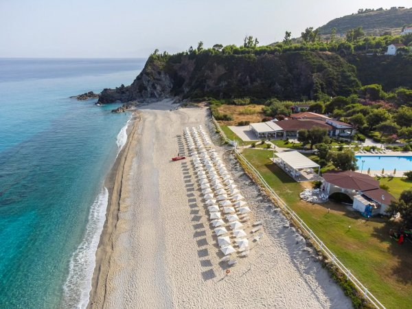 Vista aerea di una spiaggia con ombrelloni e mare turchese.