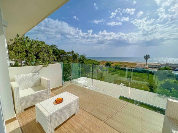Balcone con vista mare e sedie bianche.