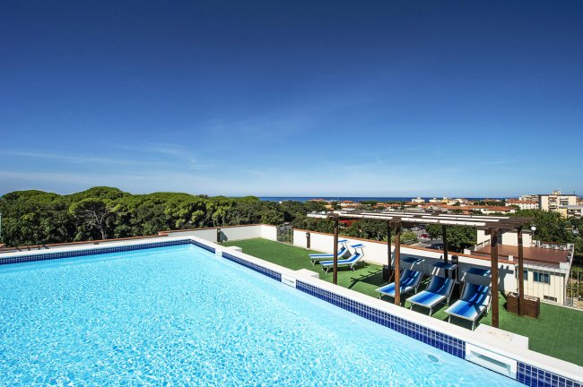 Piscina azzurra sul tetto con vista panoramica e lettini.