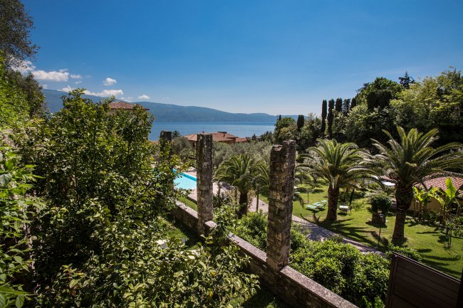 Giardino verde con vista lago e monti sullo sfondo.